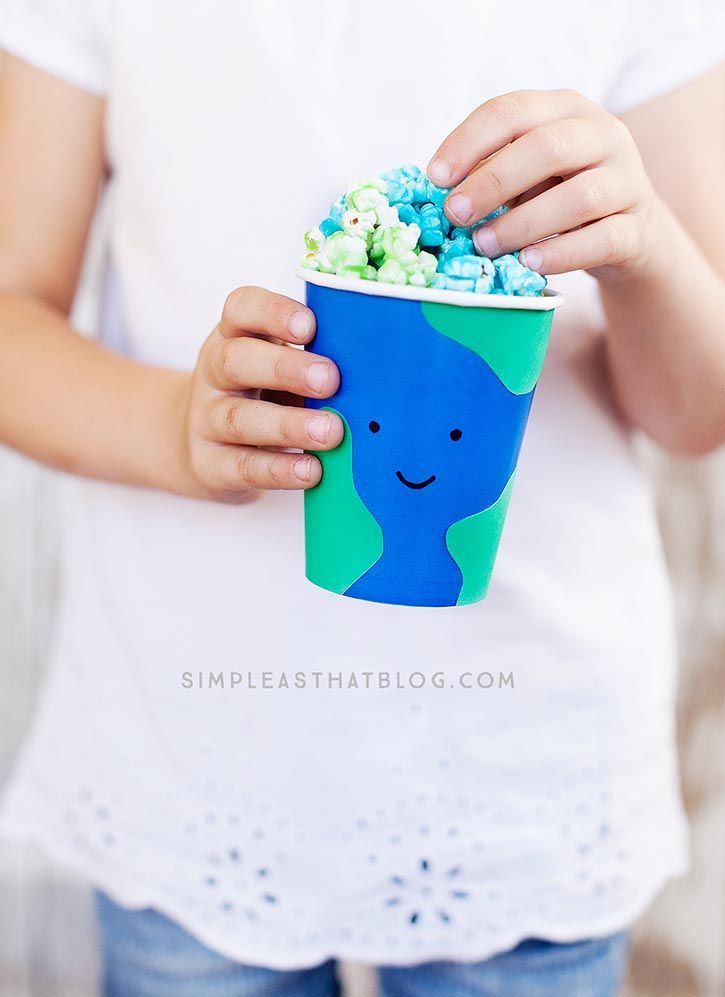 a person holding a blue cup filled with popcorn