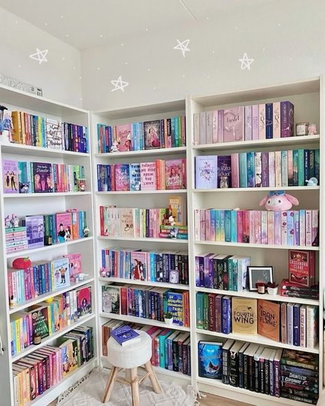 a room filled with lots of books on white shelves