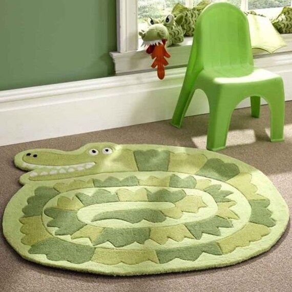 a child's room with a green chair, rug and toy snake on the floor