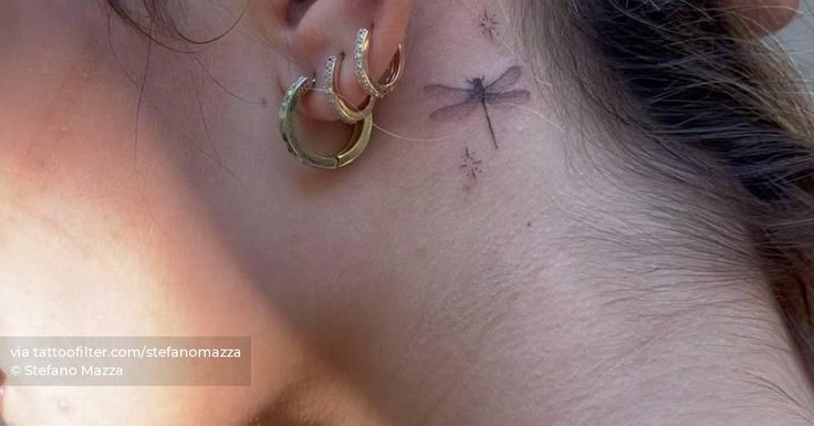 a woman's ear has a cross tattoo on it