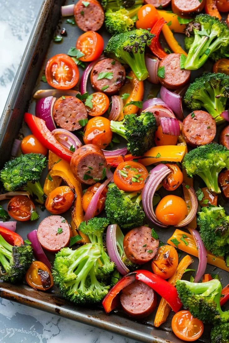 a sheet pan filled with sausage, broccoli and red onion stir - fry