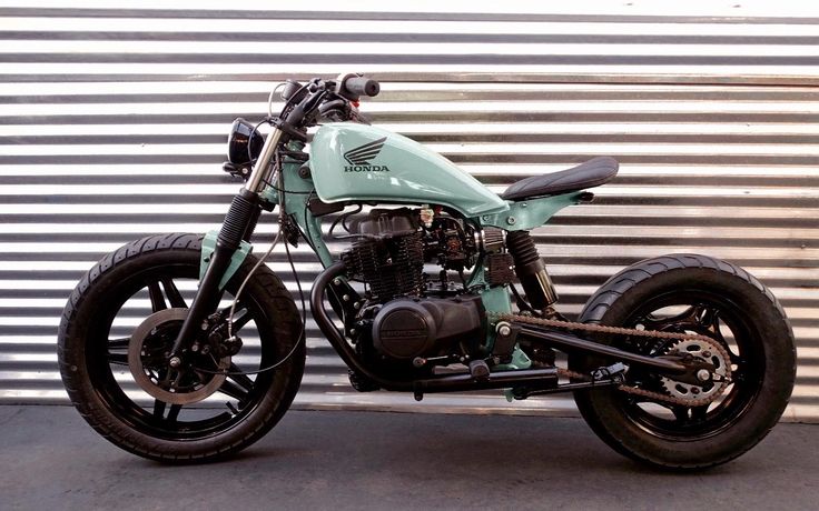 a green motorcycle parked in front of a metal wall with no one on it's bike