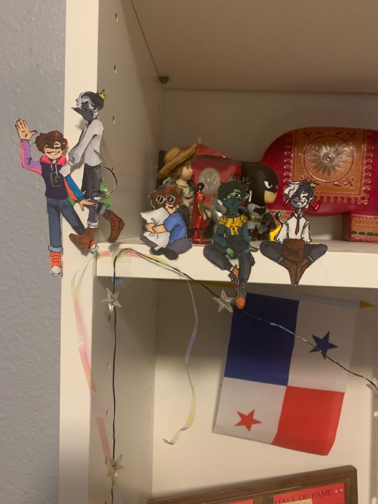 the shelf is filled with paper dolls and other items