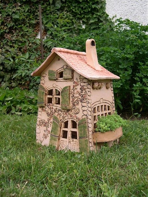 a small clay house sitting in the grass