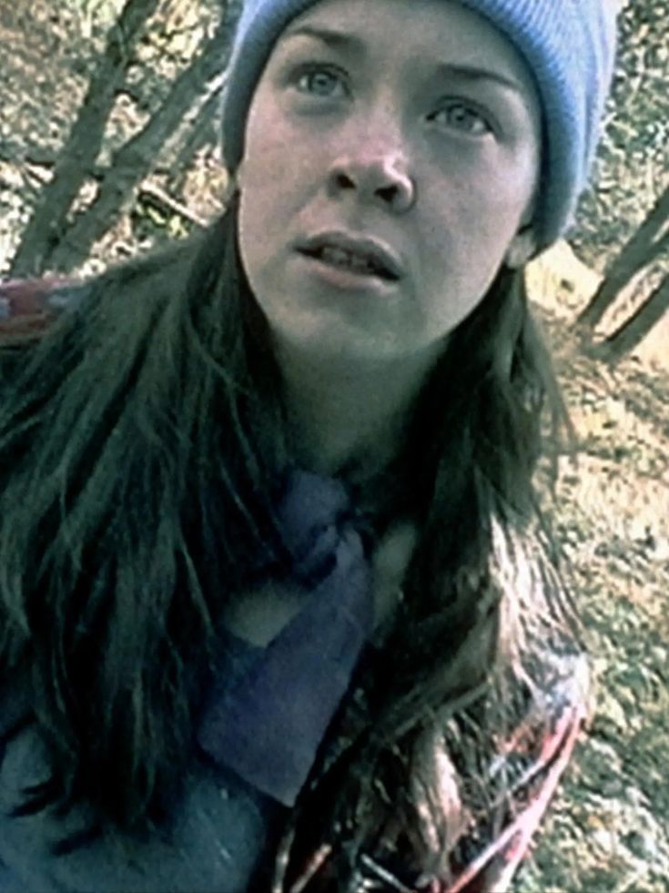 a woman with long hair wearing a blue beanie and looking up at the camera