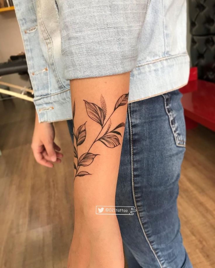 a woman with a tattoo on her arm and leg is standing in front of a wooden floor