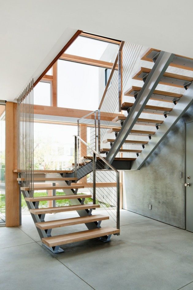 a stair case with metal railing and wooden handrails in front of a large window