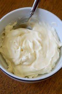 a white bowl filled with cream on top of a wooden table