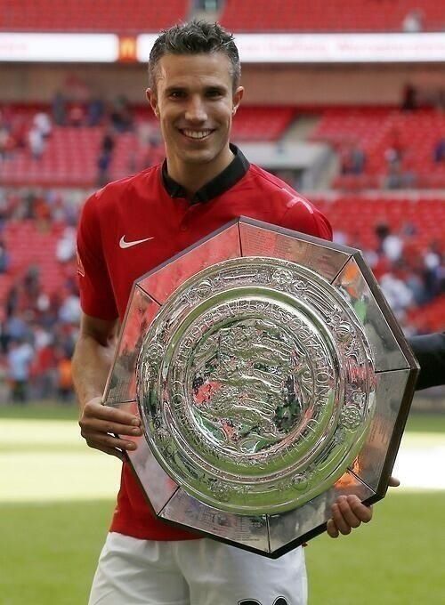 a man holding up a soccer trophy on top of a field