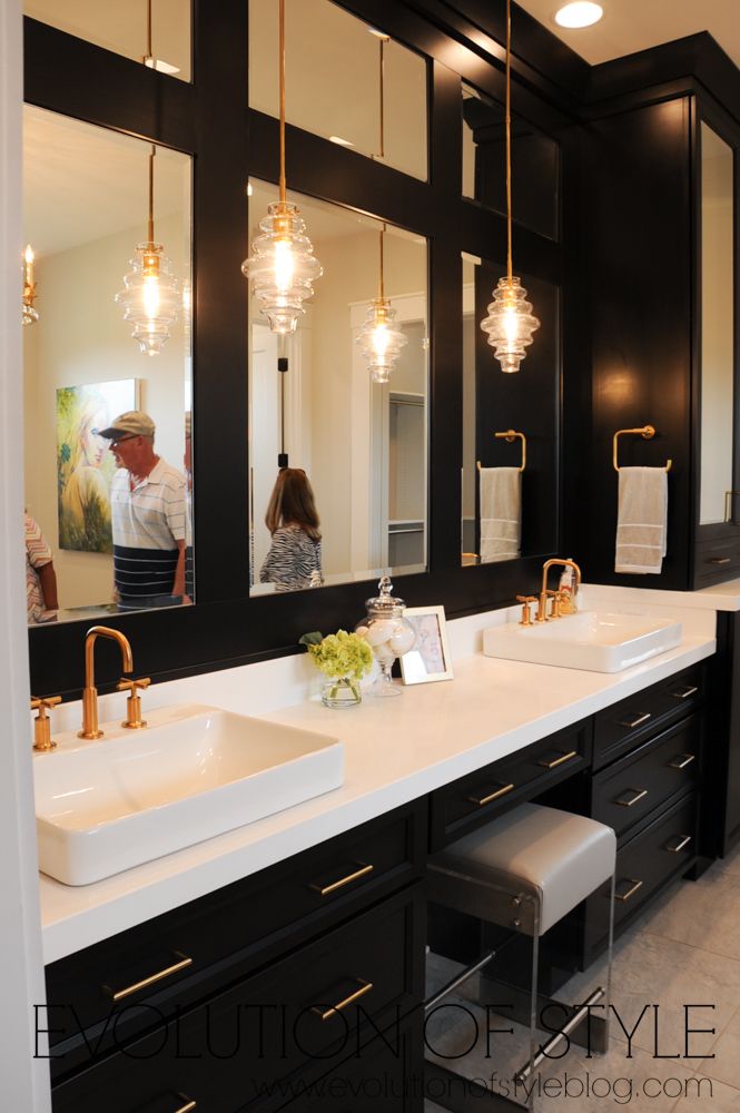 a couple of sinks in a bathroom with lights hanging from the ceiling and mirrors on the wall