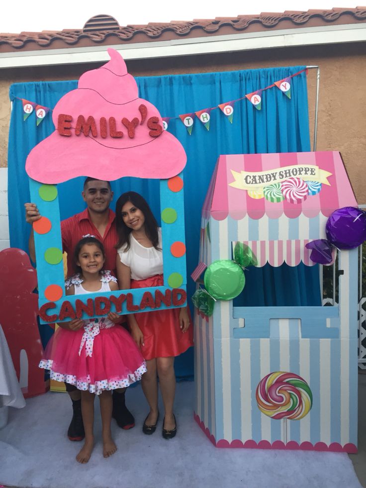 a family poses in front of a candy shop booth at an amusement park or carnival