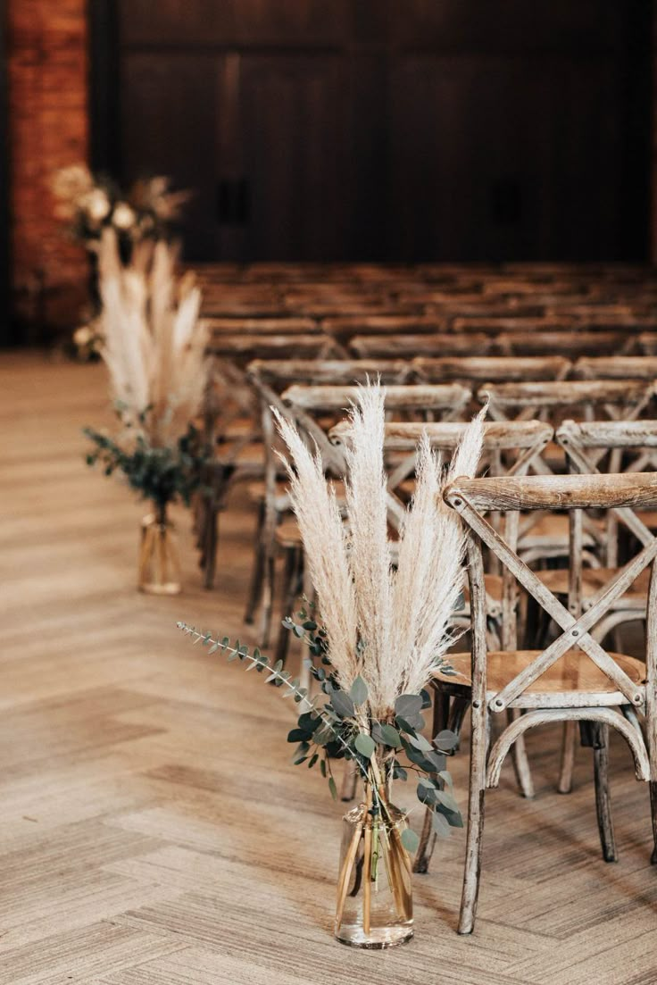 an aisle with chairs and flowers in vases