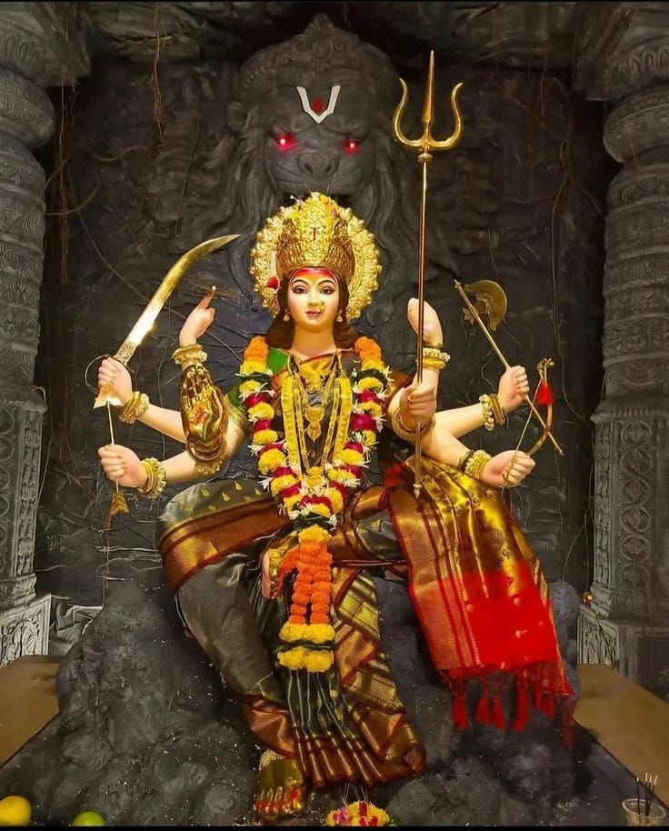 a statue of a woman sitting on top of a pile of rocks and holding two spears