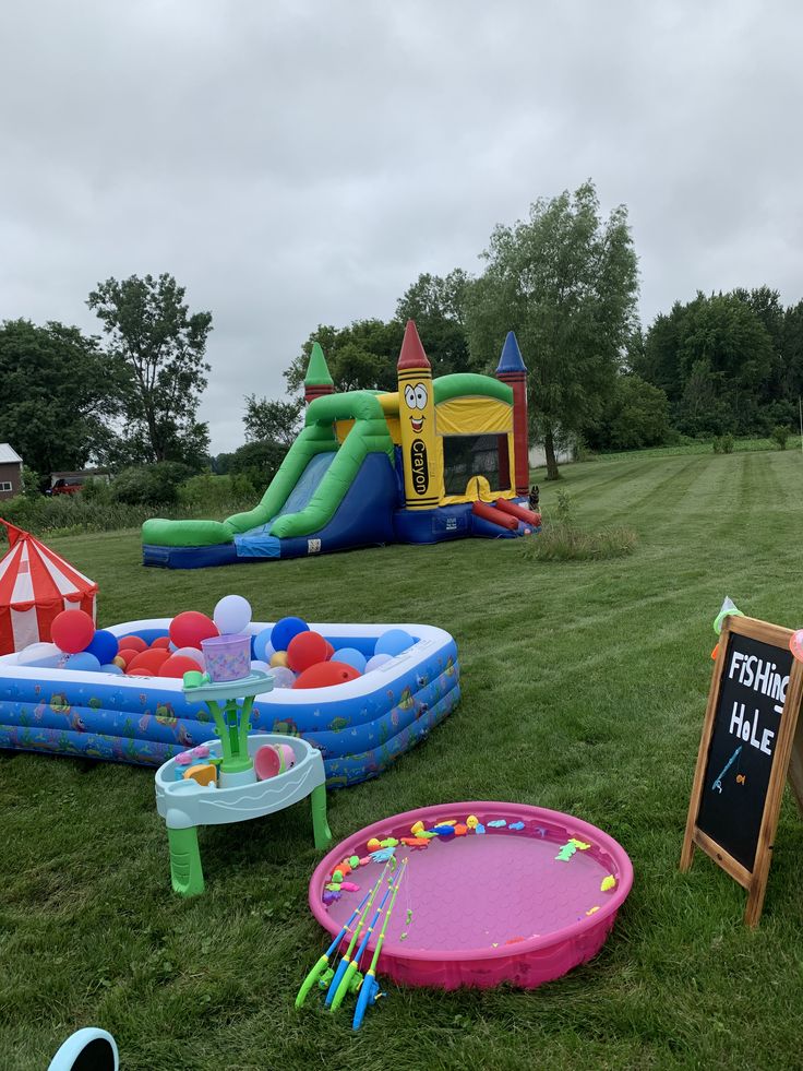 an inflatable bounce house and pool are set up on the lawn for a birthday party