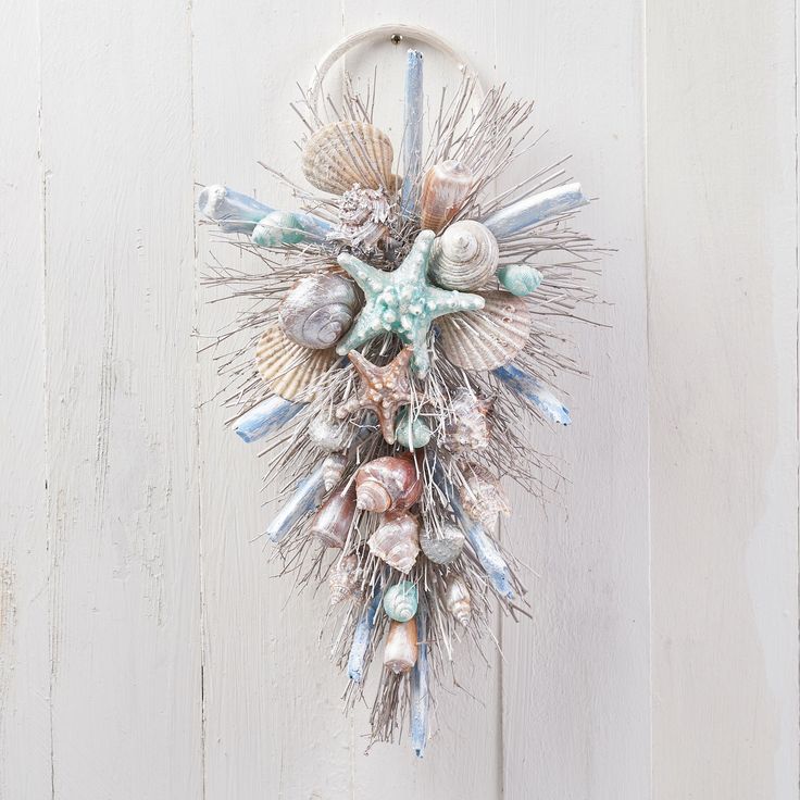 a wall hanging with seashells and sea urns on it's side