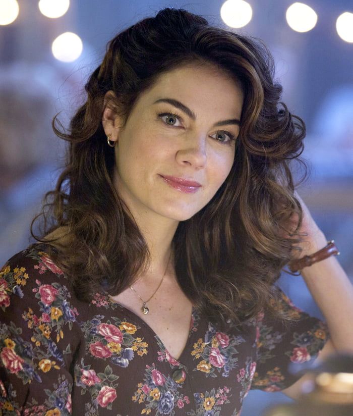 a close up of a person wearing a flowered shirt and smiling at the camera