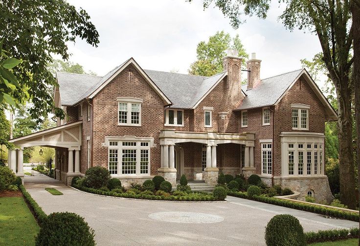 a large brick house with lots of windows and bushes around it's front entrance