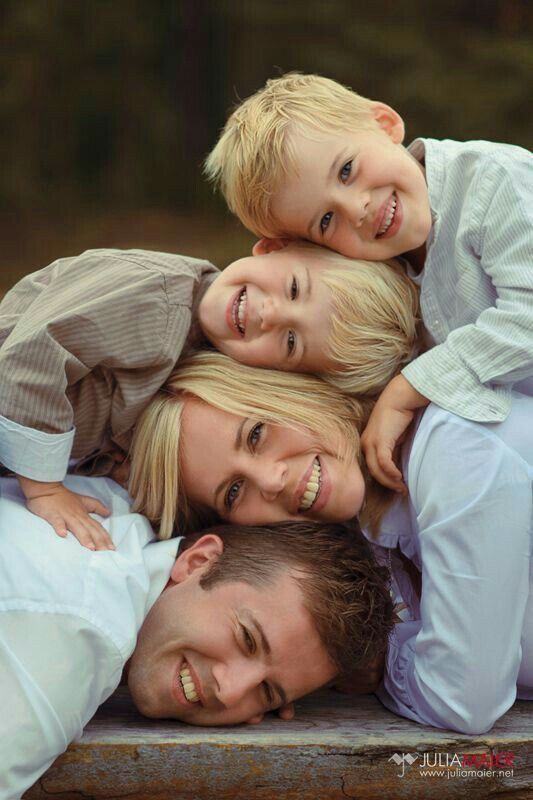 a family is laying down together in the middle of their heads and smiling at the camera