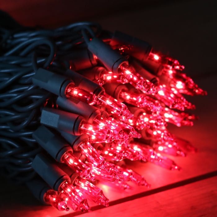 red christmas lights are laying on top of each other in the dark, with black cords