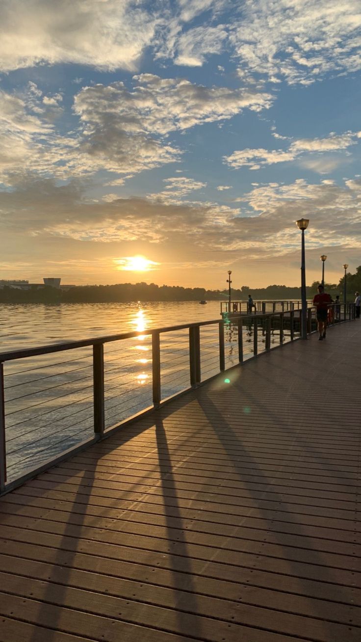 the sun is setting over the water on the pier