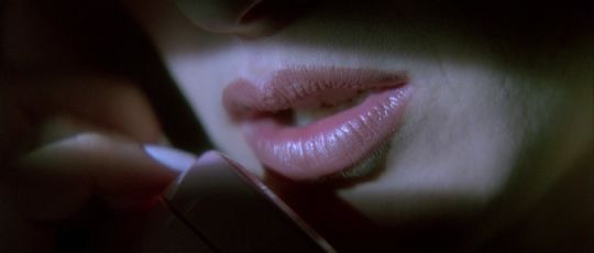 a close up of a person holding a cell phone in their hand and touching her lips