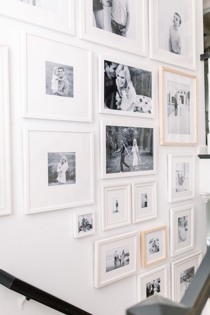 a wall with many pictures on it and stairs leading up to the second floor in front of them