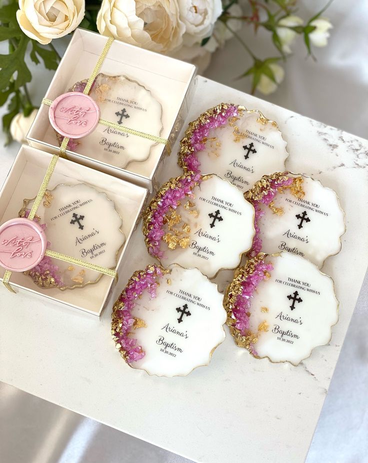 four decorated cookies sitting on top of a table next to white flowers and greenery