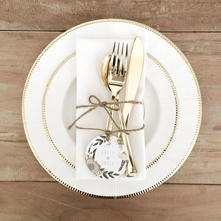 a white plate topped with a fork and knife next to a tag on a wooden table