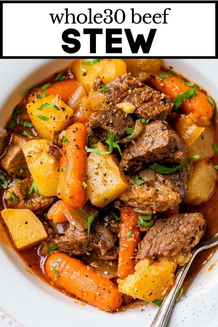 a white bowl filled with beef stew and carrots next to a fork on a plate