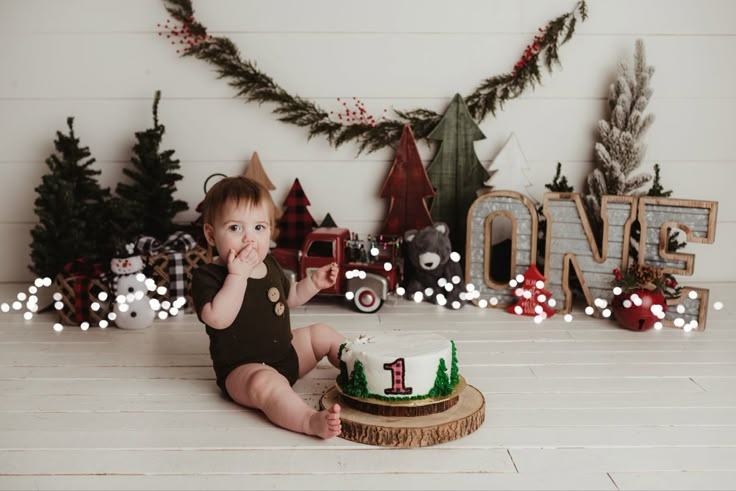 a baby sitting in front of a cake with the number one on it's side