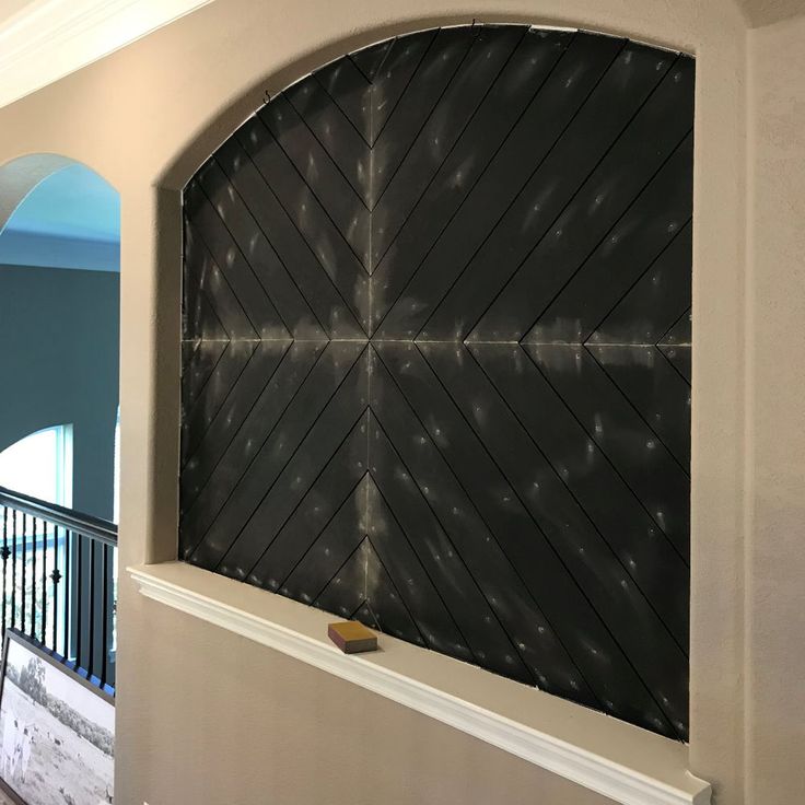 an arched window in the middle of a wall with a black and white design on it