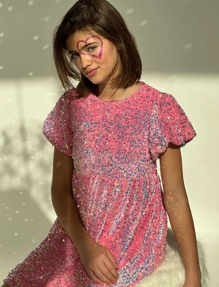 Description: Dazzling pink sequin dress covered in shimmering iridescent sequins, perfect for girls who love to sparkle. Eye-catching all-over sequins create a magical glow in the light, making this dress a standout piece for your child's wardrobe. Perfect for birthday parties, holiday celebrations, or any event where your little one wants to make a sparkling impression. Material & Care: Fabric: High-quality sequin overlay with soft inner lining for comfort. Care Instructions: Hand wash cold or Pink Glitter Dress For Party Season, Pink Glitter Dresses For Party Season, Cute Short Sleeve Mini Dress For Party, Pink Shimmer Party Dress, Pink Festive Dress With Sequins, Pink Sequin Dress For Festive Occasions, Pink Glamorous Sequin Dress For Festive Occasions, Glamorous Pink Sequin Dress For Festive Occasions, Playful Sequin Party Dresses