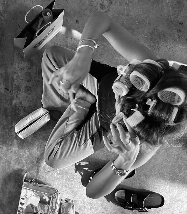 black and white photograph of a woman with goggles on looking at her cell phone