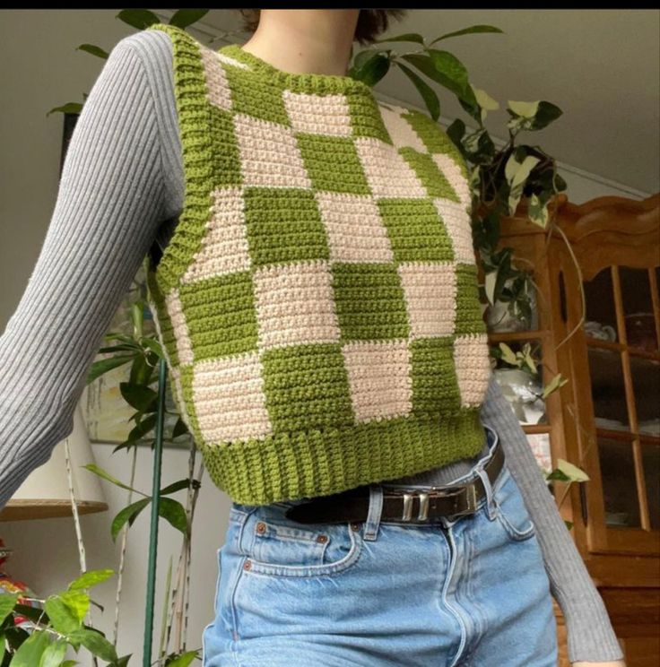 a woman is wearing a green and white knitted sweater with squares on the back