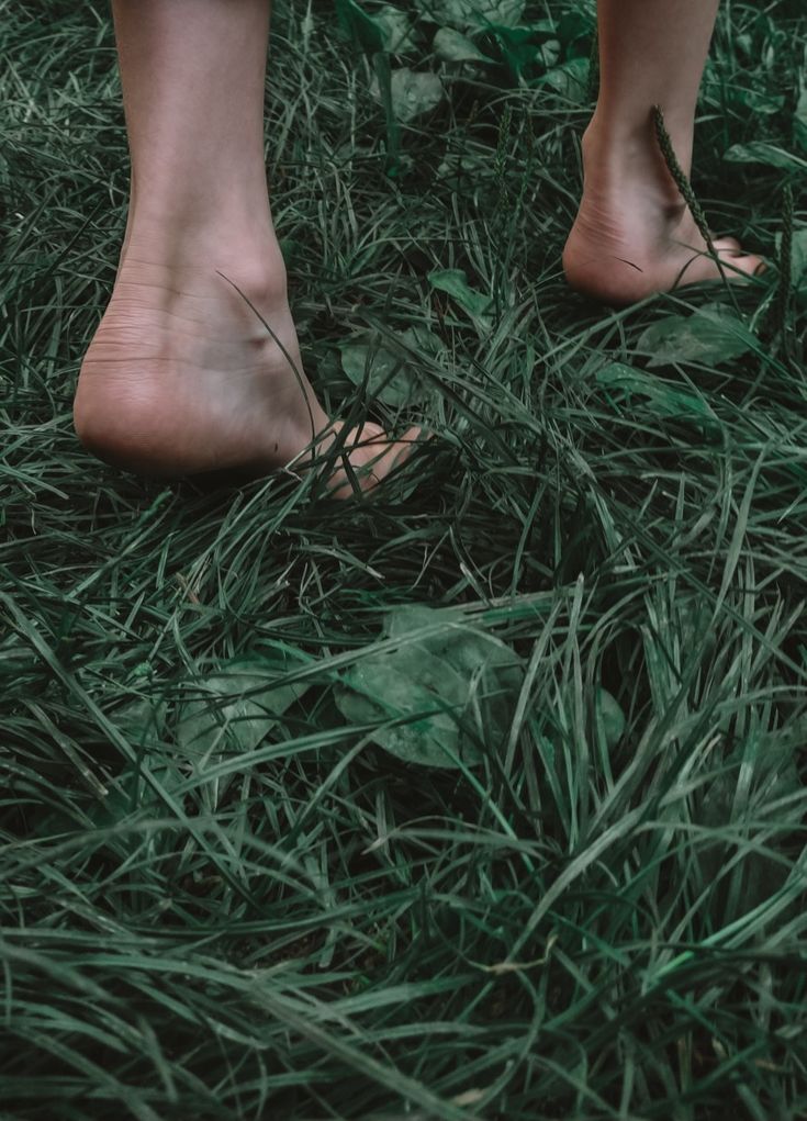 a person standing in the grass with their bare feet