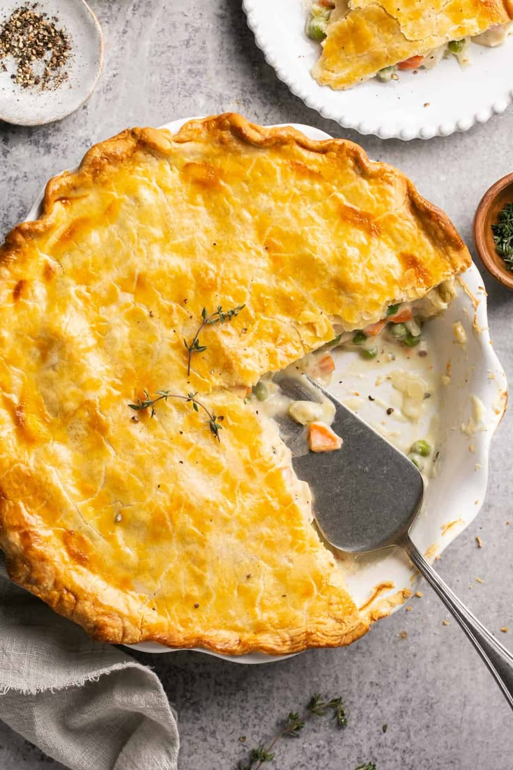 a pie with a slice missing from it on a plate next to other plates and spoons