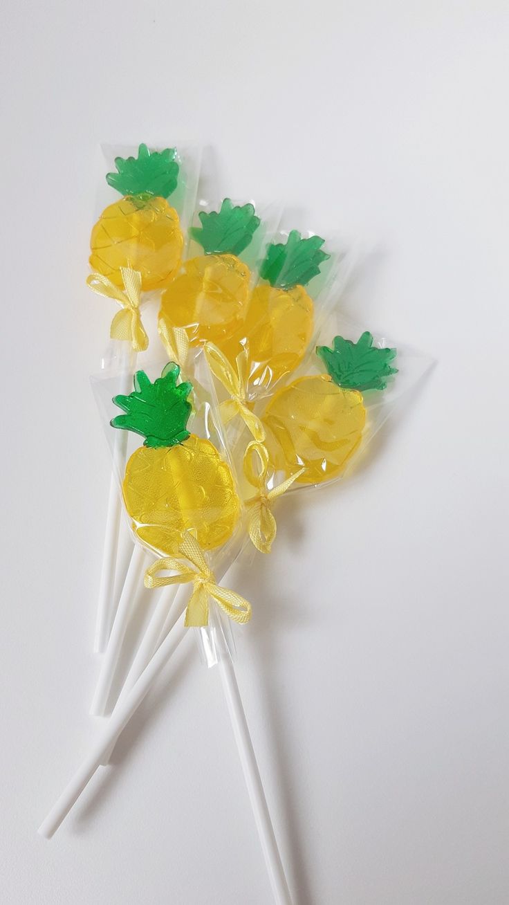 four lollipops with pineapple on them sitting on a white table top