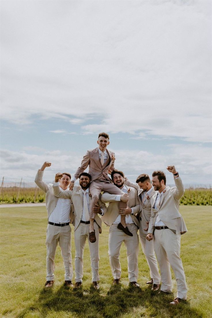 a group of men standing on top of each other in front of a lush green field