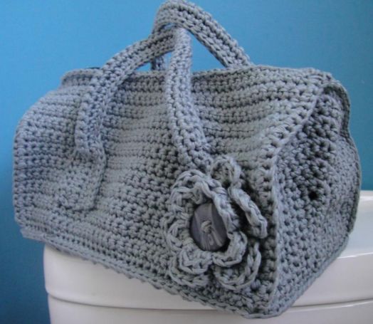 a crocheted purse sitting on top of a white toilet bowl next to a blue wall