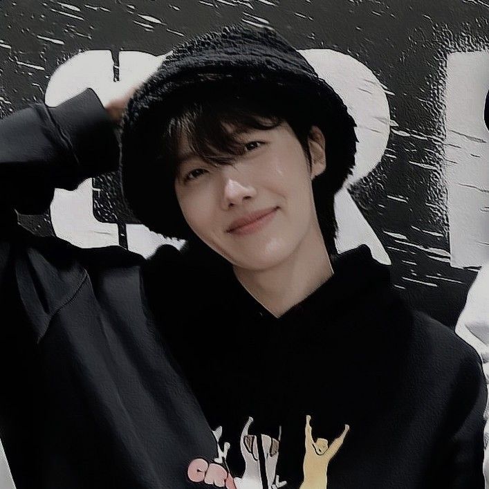 a young man wearing a black hoodie and hat posing for the camera with his hands on his head