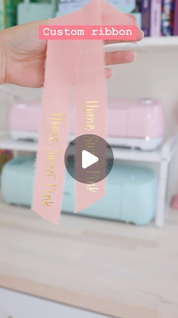 a person holding up a pink ribbon with the words custom ribbon on it in front of a shelf