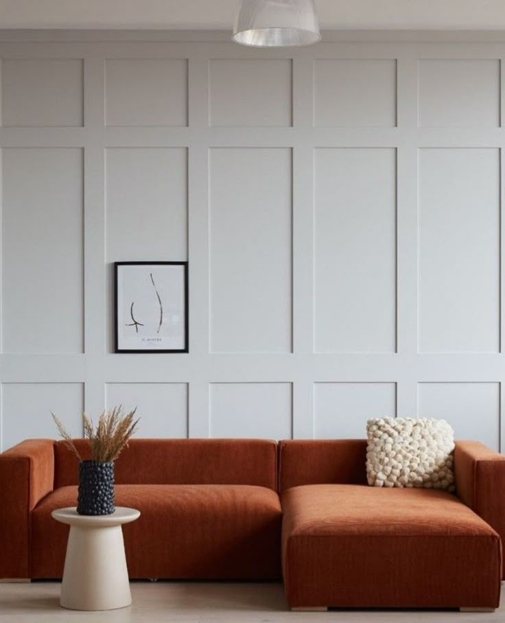 an orange couch sitting on top of a hard wood floor next to a white table