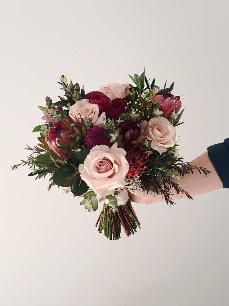 a bouquet of flowers is being held by someone's hand on a white background