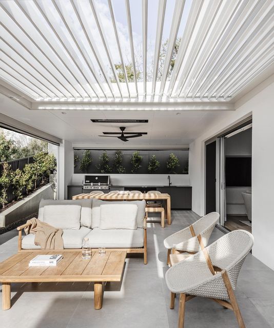 an outdoor living area with white furniture and wooden tables