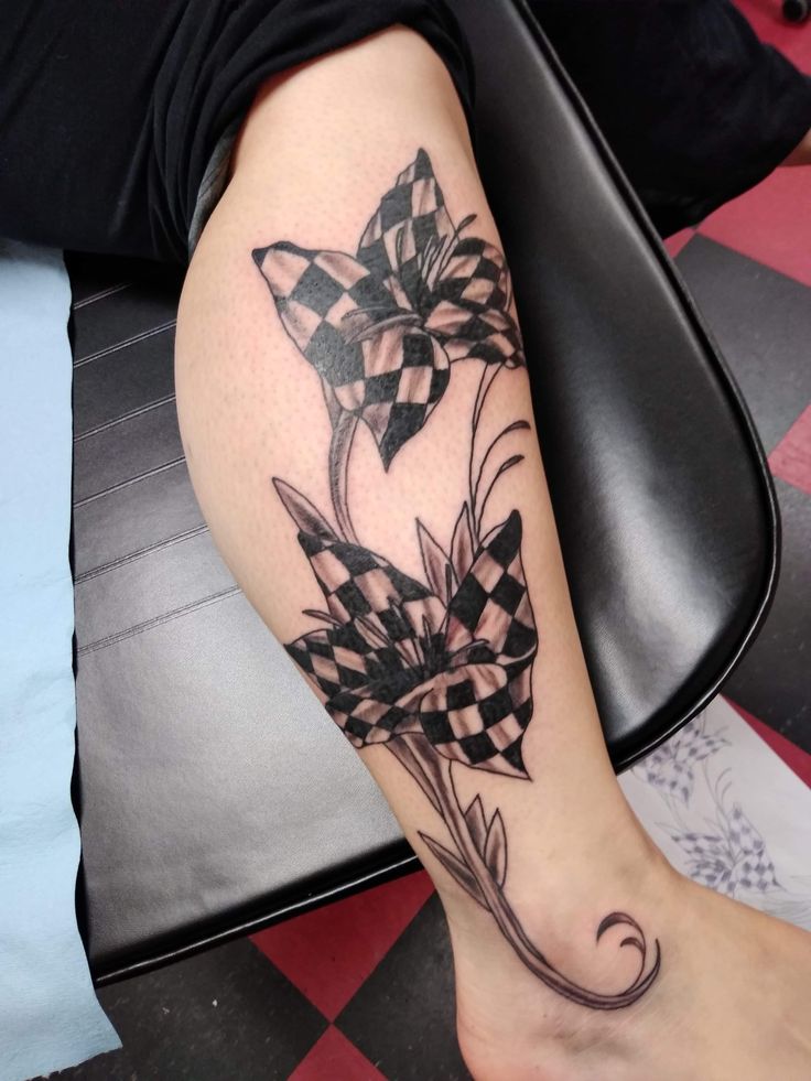 a woman's leg with a checkered flower tattoo on her left arm and foot