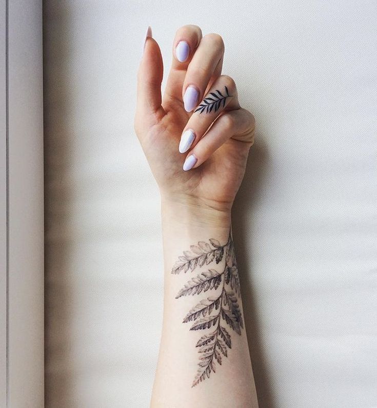 a woman's arm with a leaf tattoo on the left side of her hand