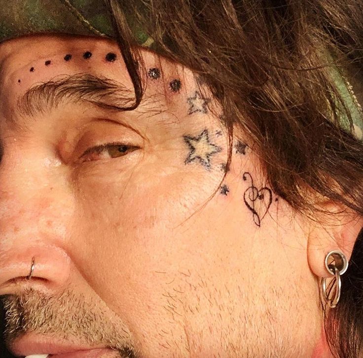 a close up of a person with tattoos on his face and behind his ear, looking to the side