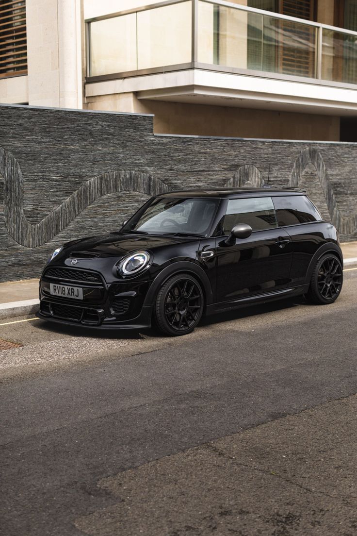 a small black car parked on the side of the road in front of a building