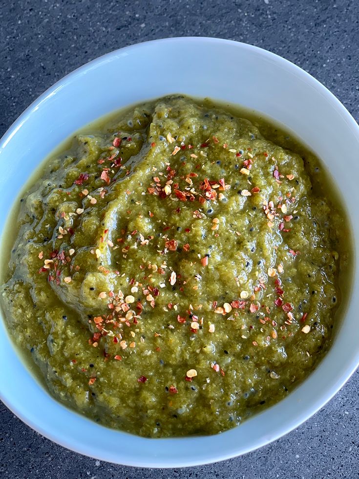 a white bowl filled with green sauce and sprinkles