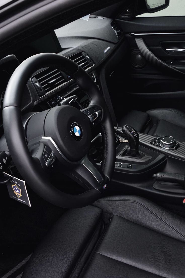 the interior of a bmw car with black leather seats and steering wheel, including an electronic display